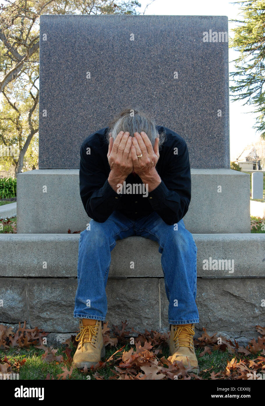 Mann, sitzend am Grab mit seinen Kopf in seine Hände Stockfoto