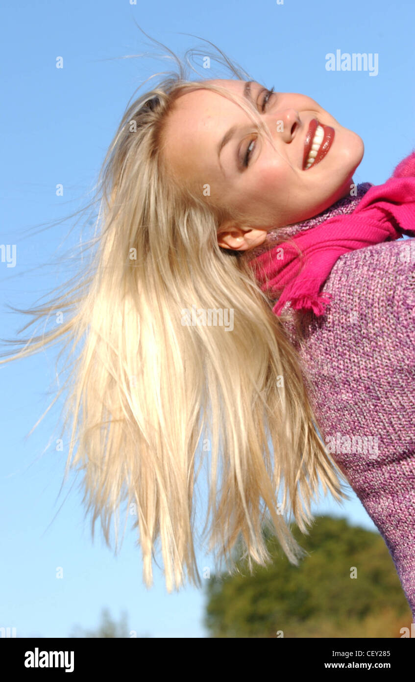 Weibliche lange blonde Haare braun Tönen des Make-up tragen lila Pullover hell rosa Schal und Handschuhe zurückgelehnt Lauft zurück Stockfoto