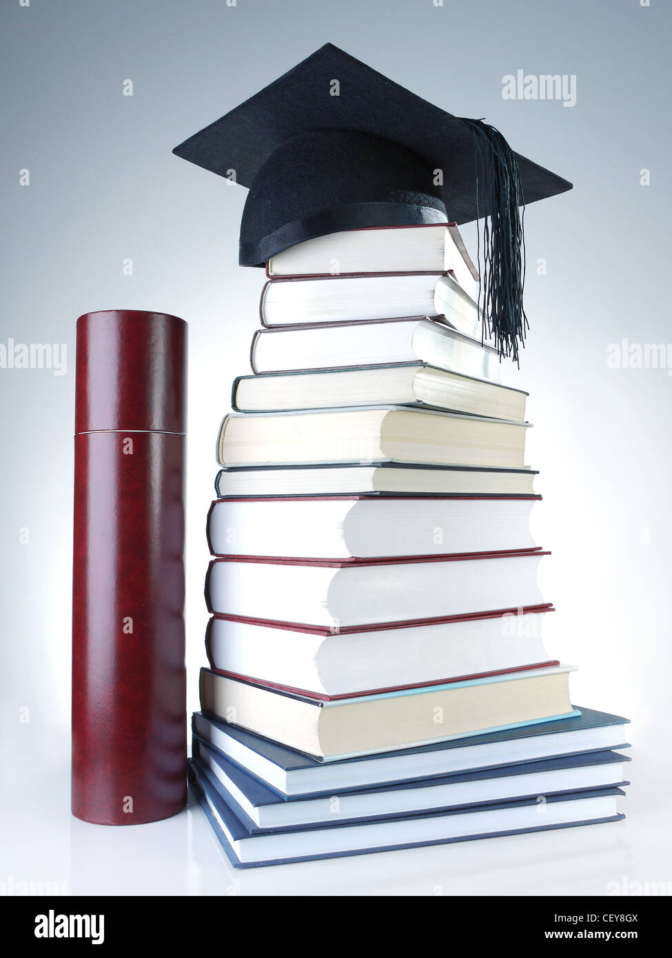 Schwarze Graduierung Kappe auf Stapel Bücher mit Diplom tube Stockfoto