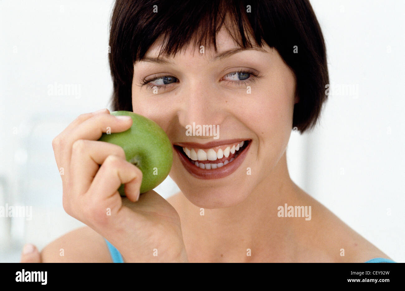 Eine Frau auf der Suche nach rechts hält einen grünen Apfel Stockfoto