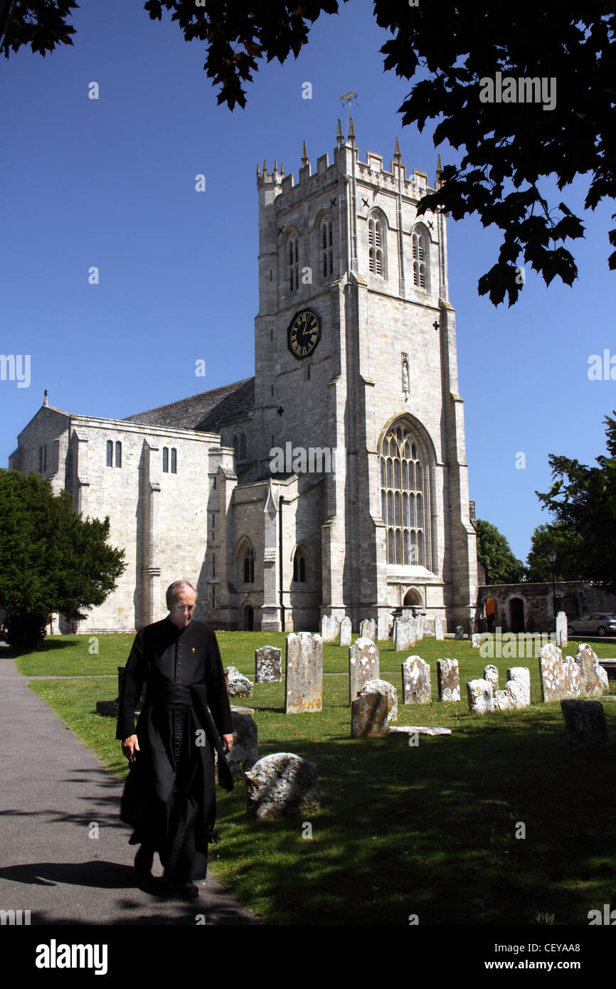 Der Priory Kirche Pfarrei von Christchurch, Dorset South West England mit einem vorbeifahrenden Priester Stockfoto