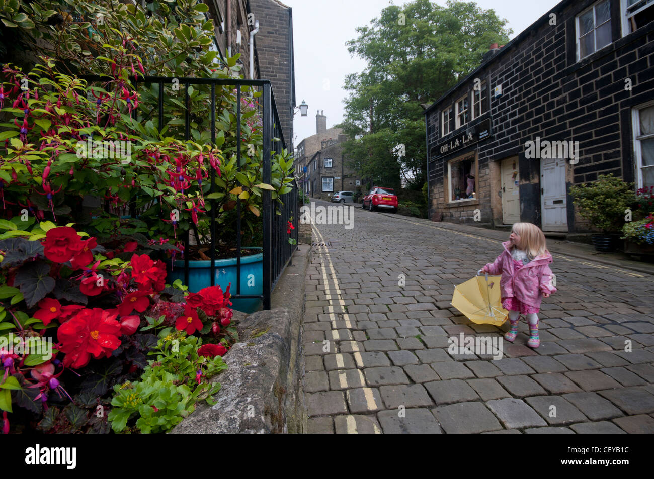 Kleines Kind mit Regenschirm in Haworth High Street. Stockfoto