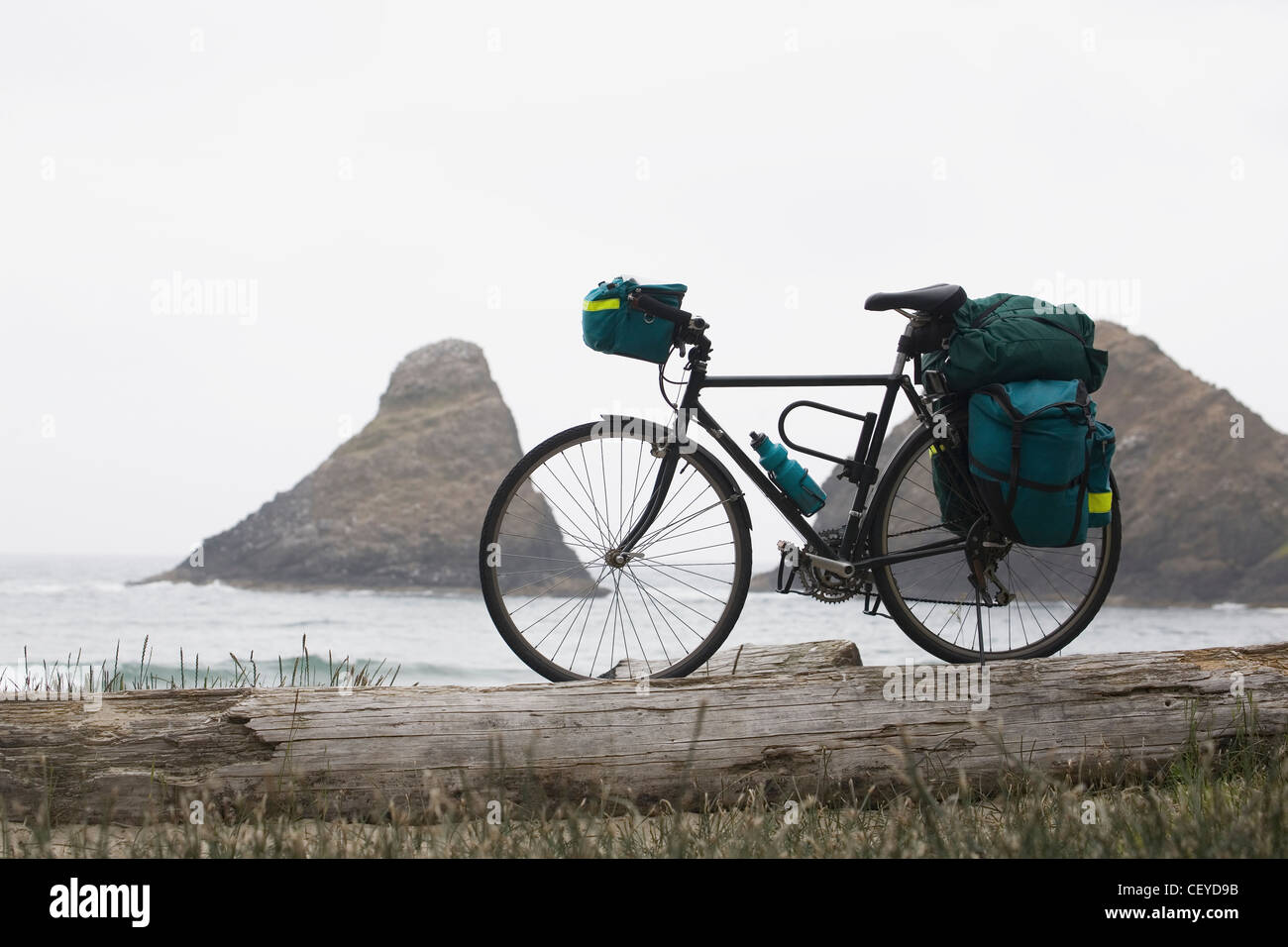Touring Fahrrad mit vollen Taschen an einem Strand mit Felsformation im Ozean im Hintergrund; Heceta head Oregon USA Stockfoto