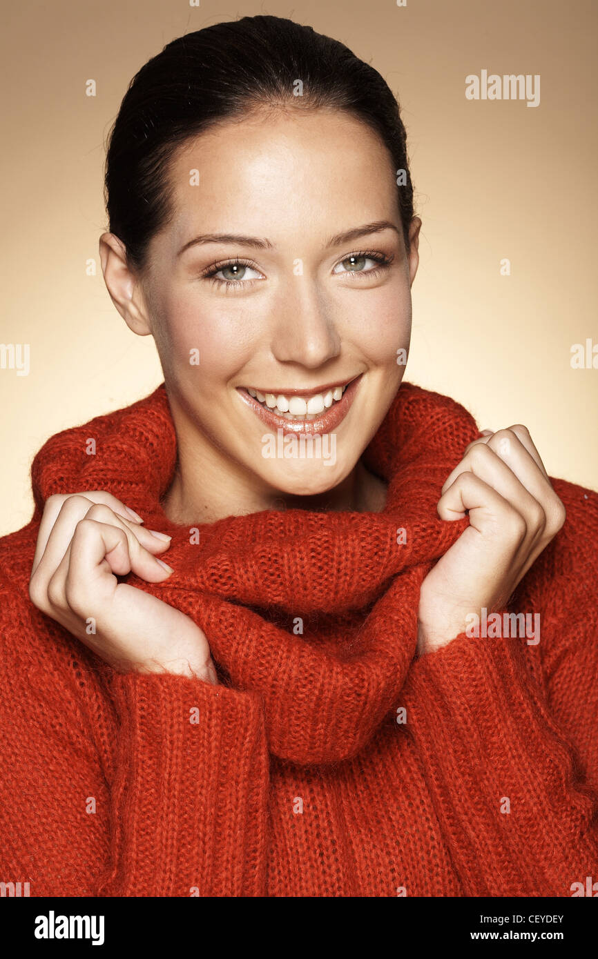 Weibchen tragen einen roten Kutte Hals Pullover mit den Händen auf dem Kragen Stockfoto