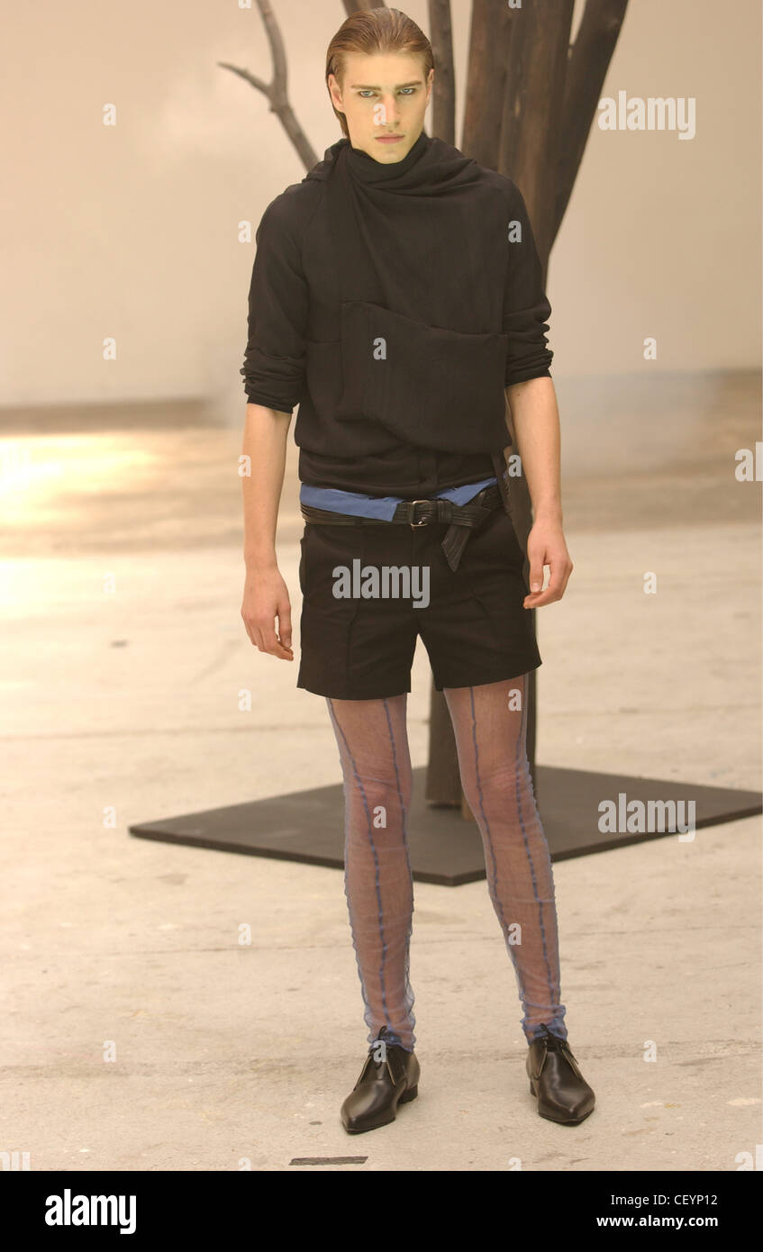 Spastor Paris Menswear S S Männermodel schwarzes Oberteil tragen um den Hals einzelne große Fronttasche versammelt; schwarze Shorts und Stockfoto