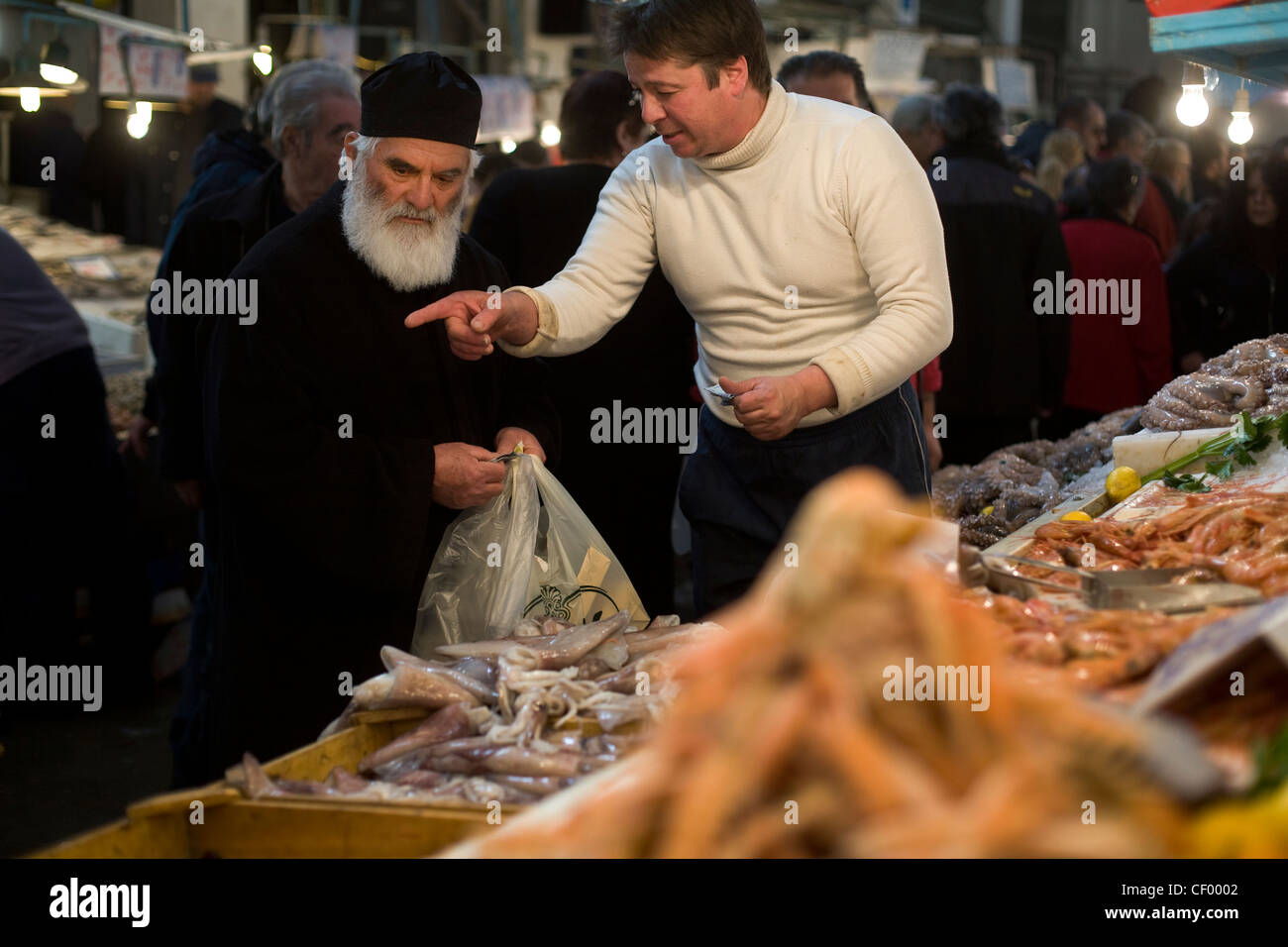 Griechisch-orthodoxe Priester kauft Meeresfrüchte aus einem Stall in Athen Zentralmarkt auf Athinas Street. Athen, Griechenland Stockfoto