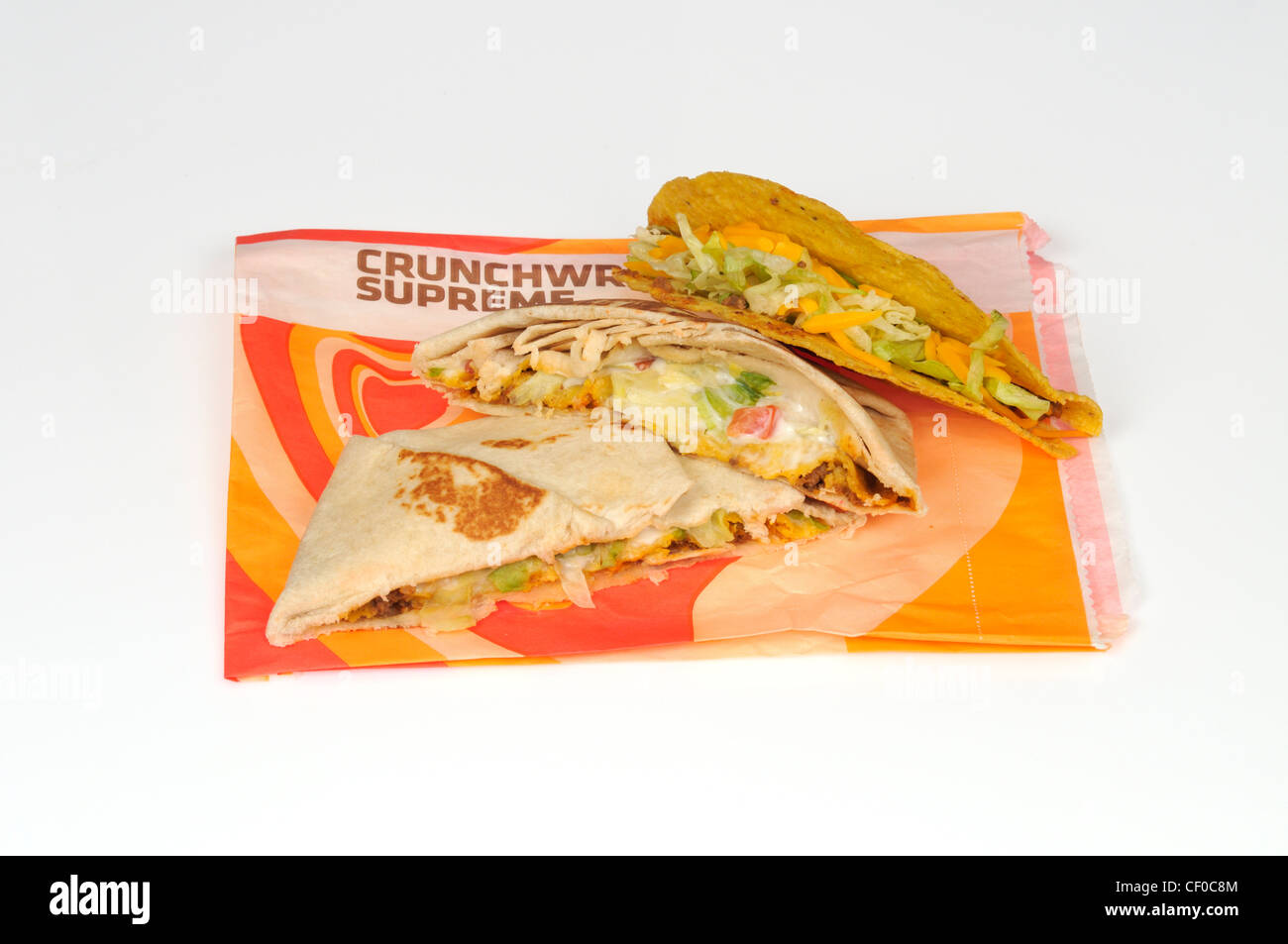Taco Bell Crunchwrap oberste Tortilla in zwei Hälften geschnitten und ein Taco auf Wrapper auf weißem Hintergrund Ausschnitt Stockfoto