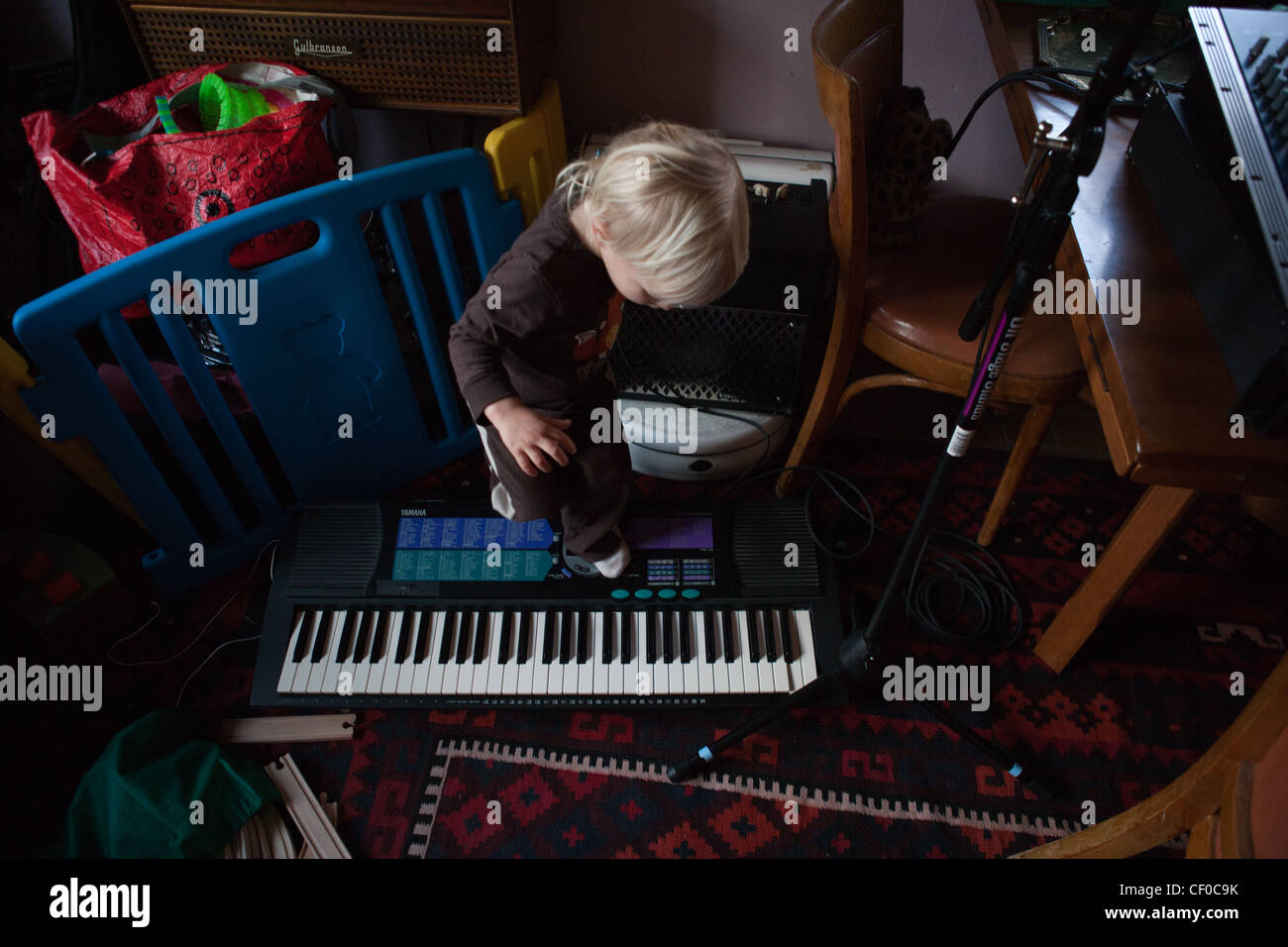 Einjähriger Junge verstärkt auf seine Eltern musikalische Ausrüstung, Keyboard und Schlagzeug Maschine. Stockfoto