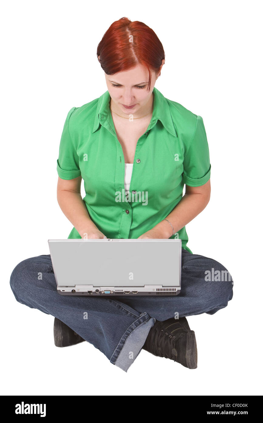 Rothaarige Teenager mit ihren gekreuzten Beinen sitzen und arbeiten auf einem Laptop. Stockfoto