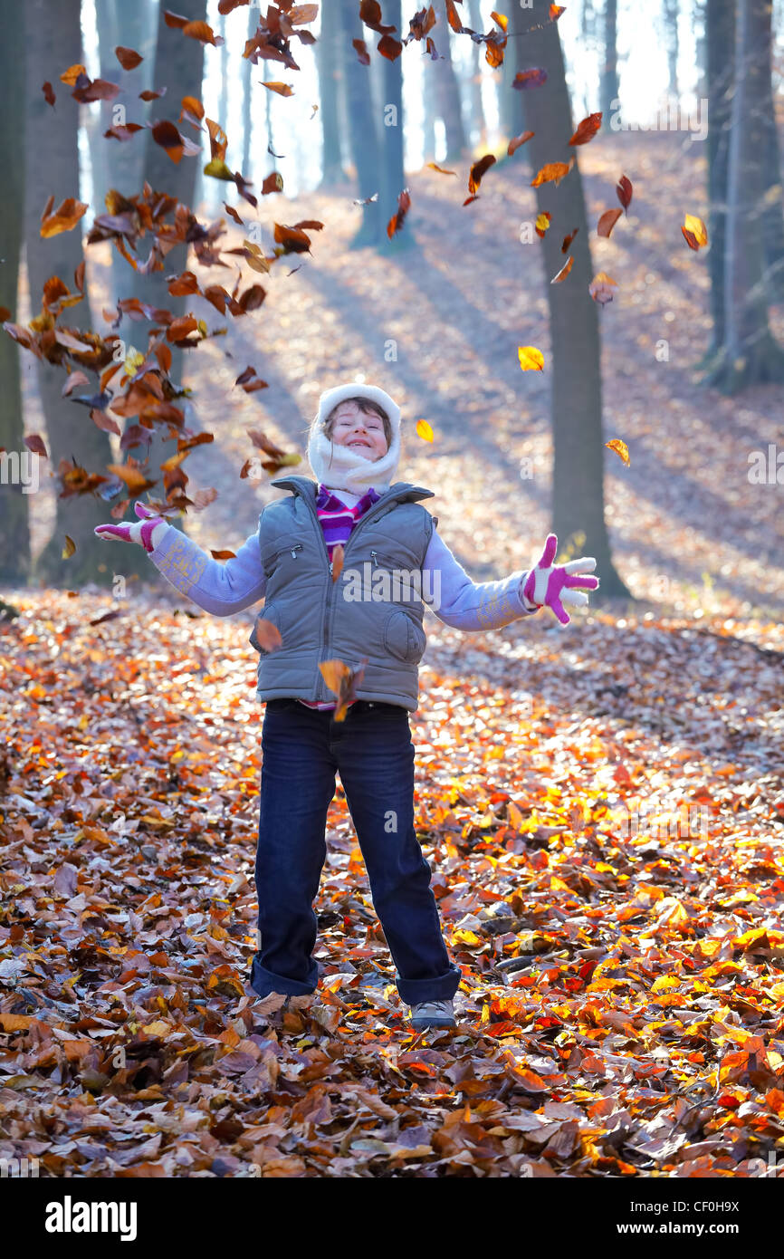 Schöne 7-jährige Mädchen genießen ein Herbsttag in den Wald werfen Blätter in der Luft. Stockfoto
