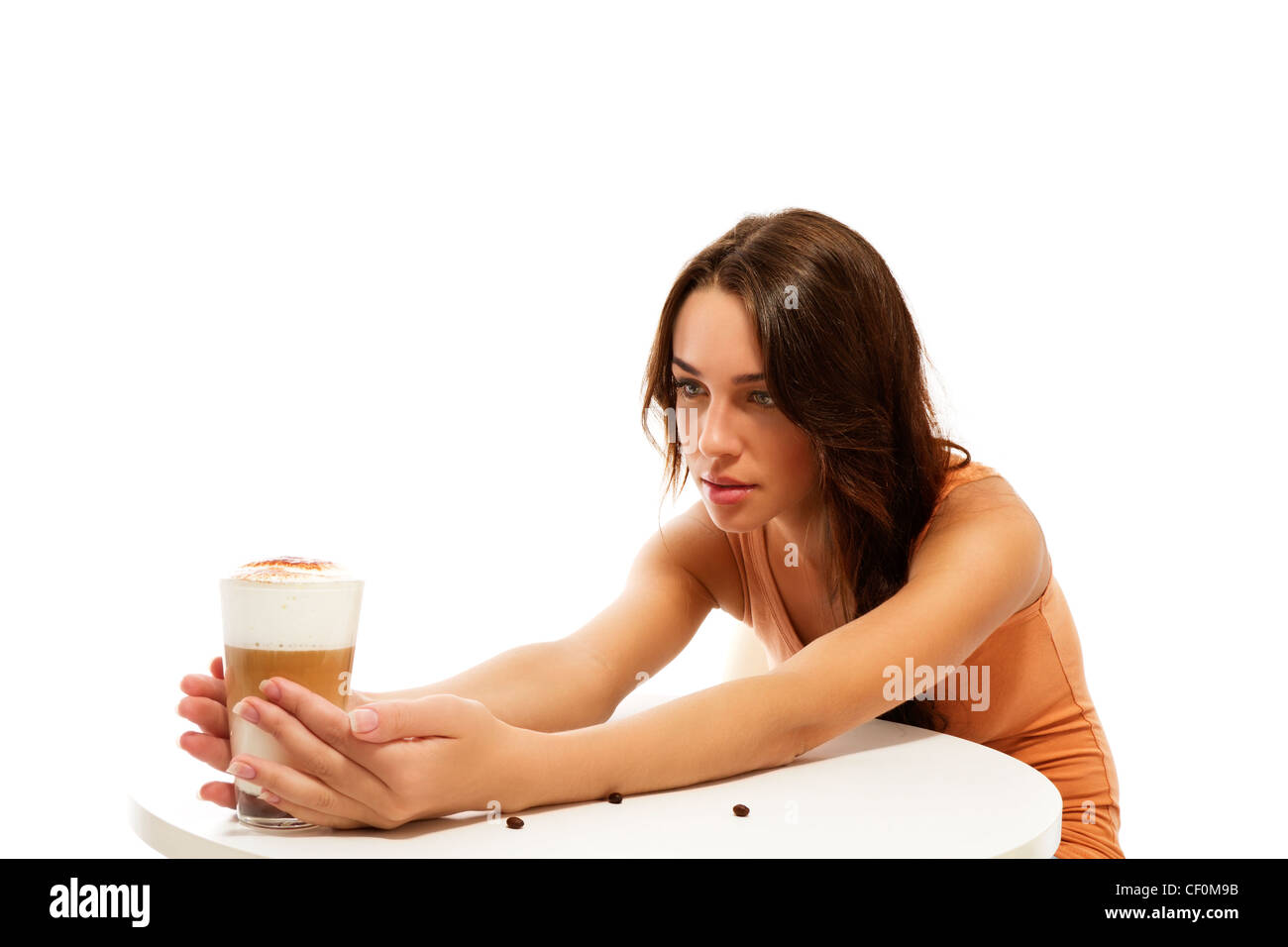 junge Frau mit Latte Macchiato Kaffee auf der anderen Seite des Tisches auf weißem Hintergrund Stockfoto