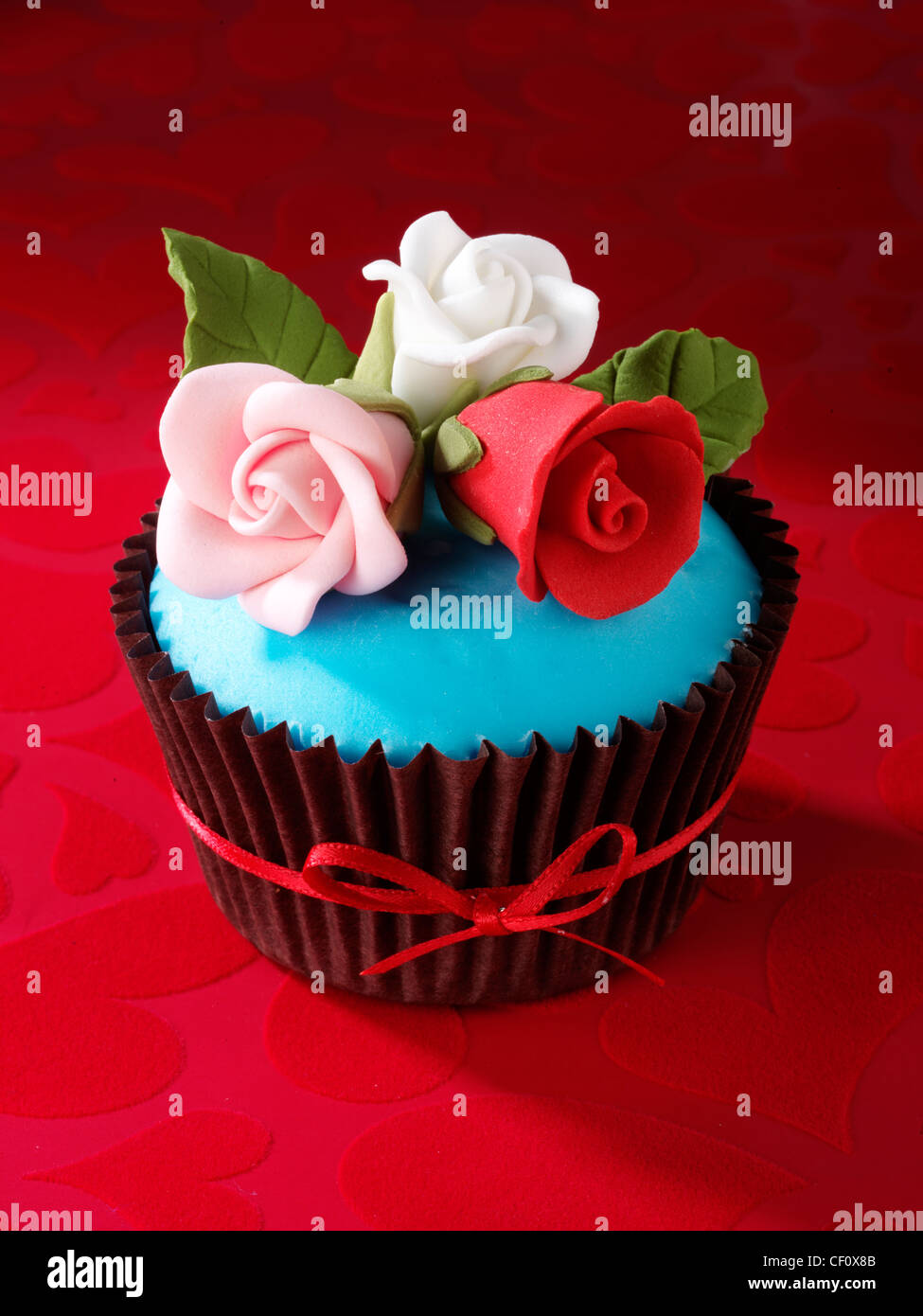 RED VELVET CUPCAKE MIT GEEISTE ROSEN Stockfoto
