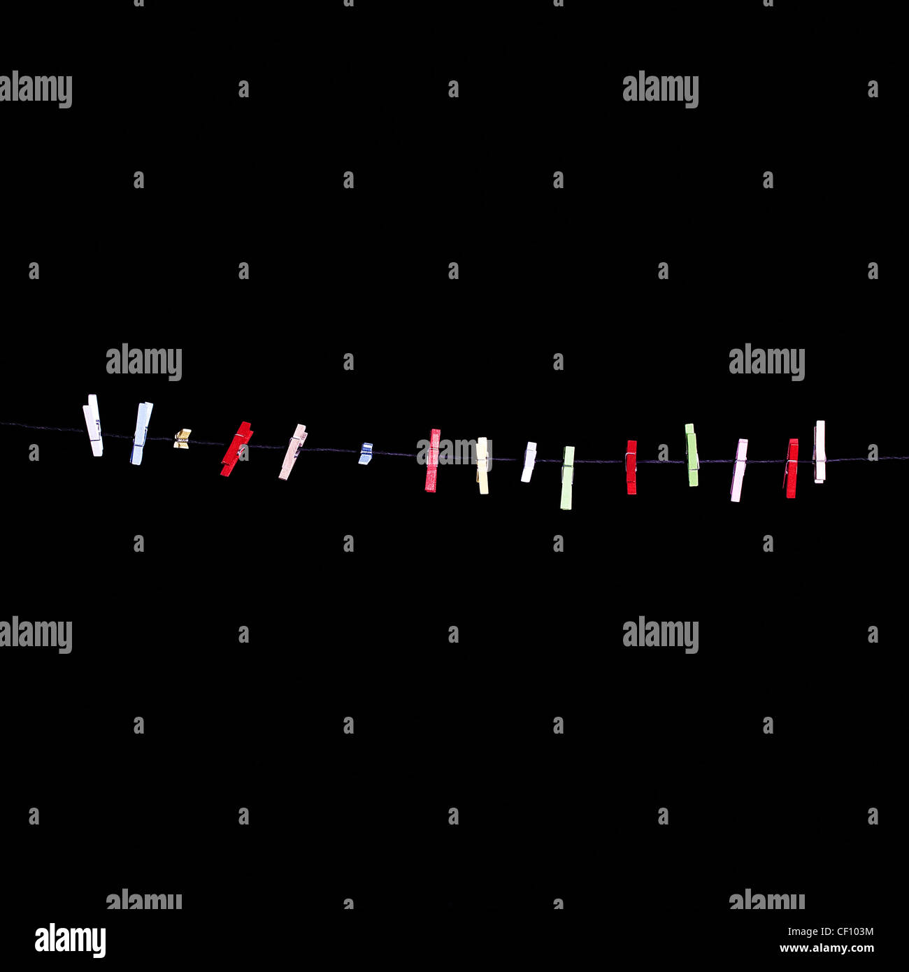 mehr bunten Wäscheklammern in einer Zeile auf einem schwarzen Hintergrund Stockfoto