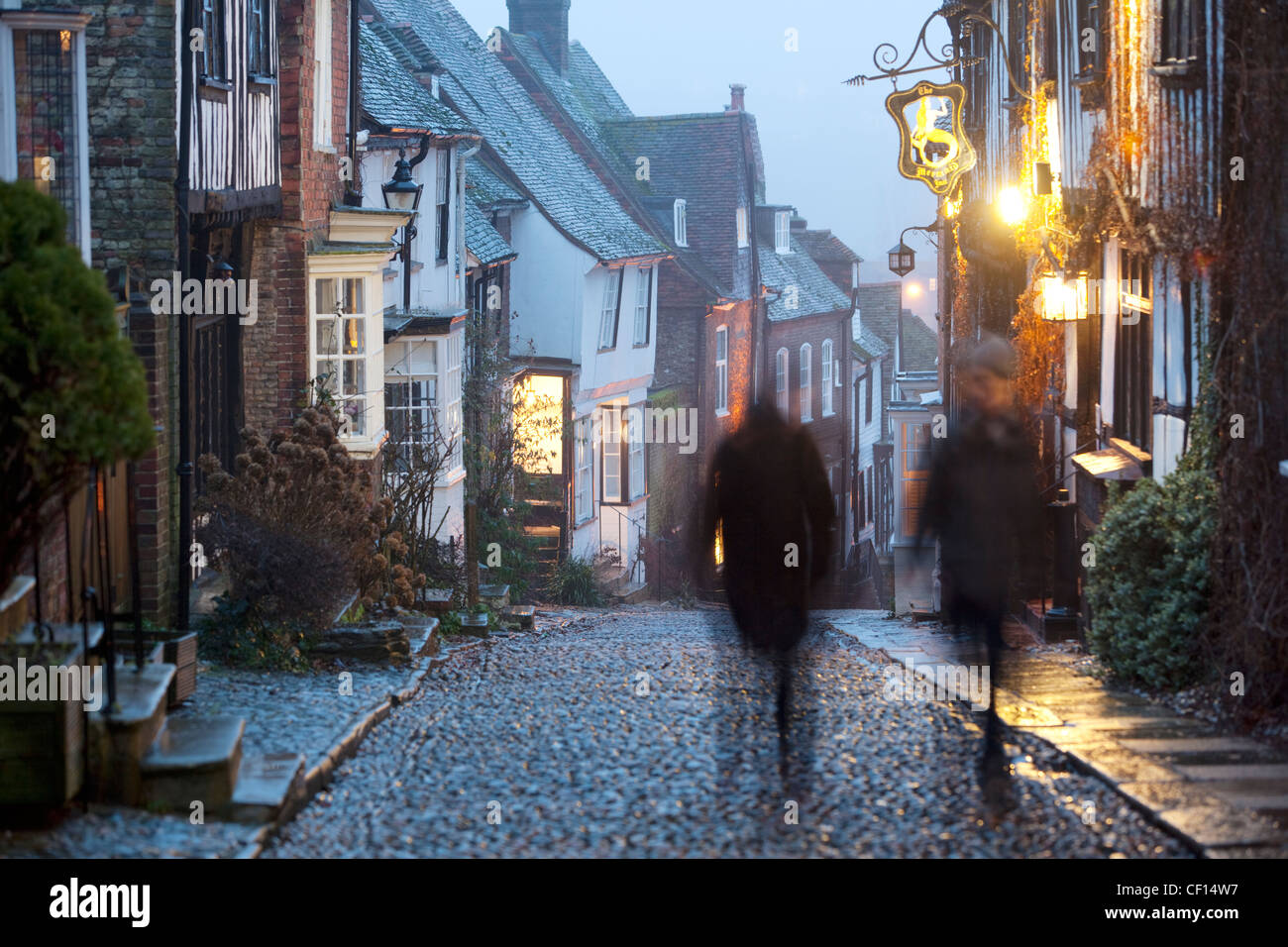 Zwei Figuren, die zu Fuß auf einer traditionellen gepflasterten Straße in Rye Stockfoto