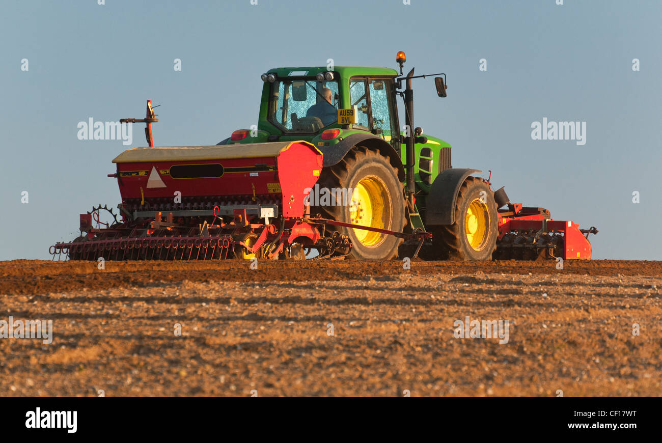 Ein Britischer Landwirt Einstellung eine Ernte mit einem landwirtschaftlichen Traktor und Drillmaschine Stockfoto