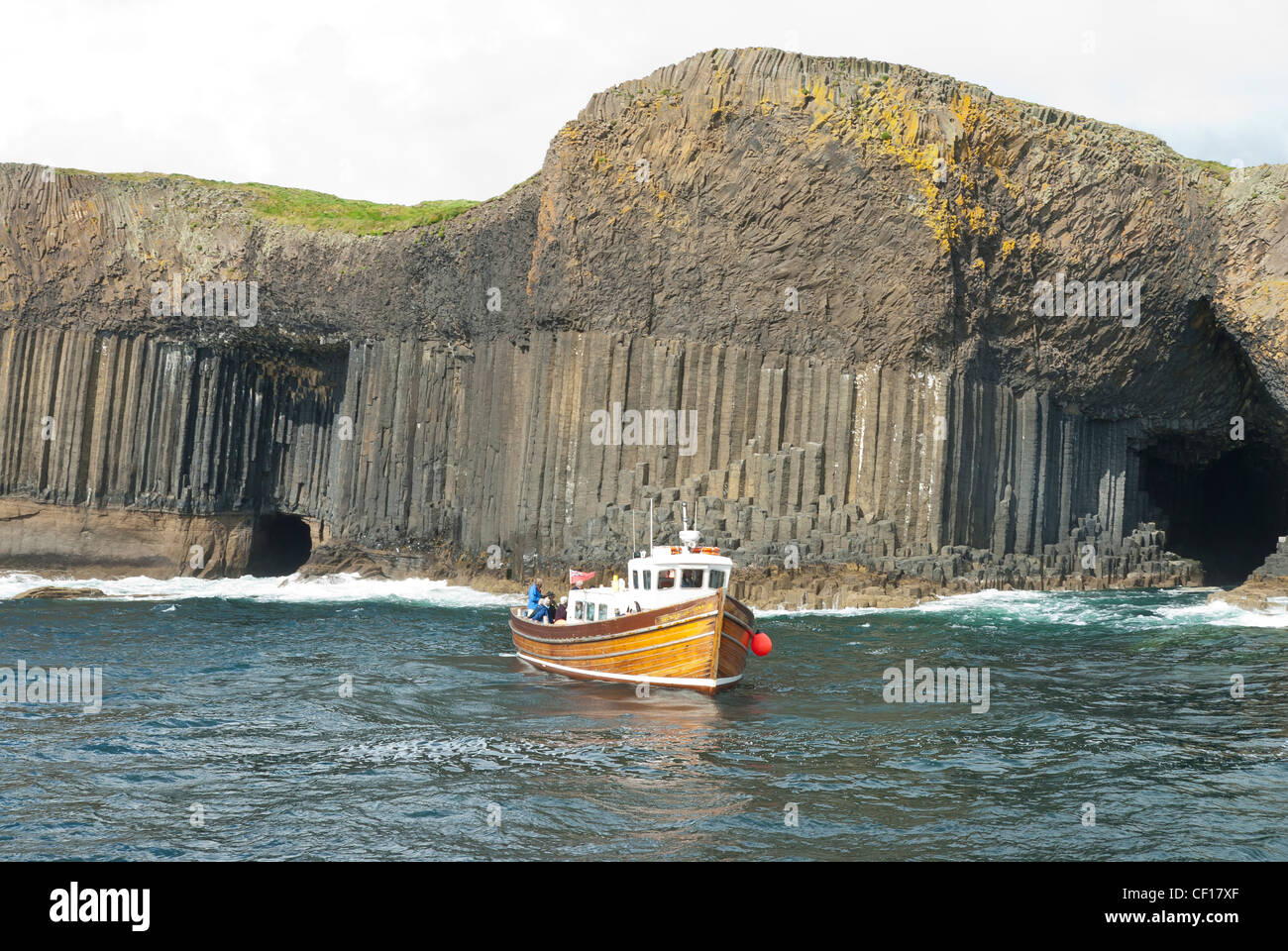 Ein Boot Kreuzfahrt entlang der Insel Staffa mit Fingals Höhle und Mackinnon es Höhle dahinter sichtbar Stockfoto