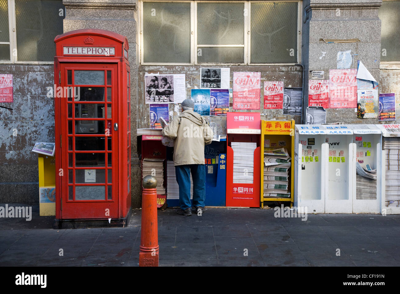 Menschen sammeln und lesen kostenlose chinesische Zeitungen aus einem Zeitungskiosk in Chinatown, London Stockfoto