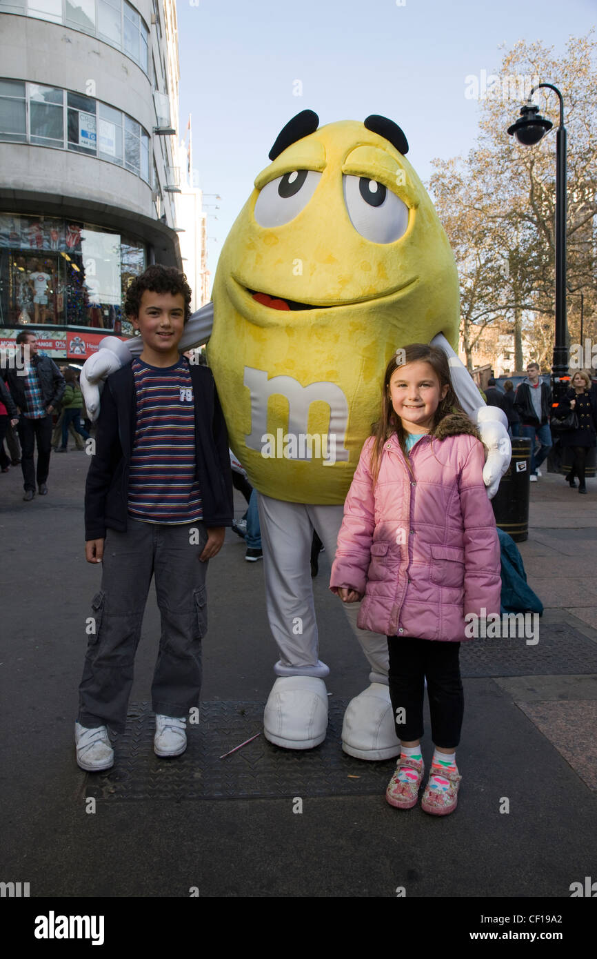 Posiert mit riesigen M & M Zeichen außerhalb der M & M Welt Konditorei in der Nähe von Leicester Square in London Stockfoto
