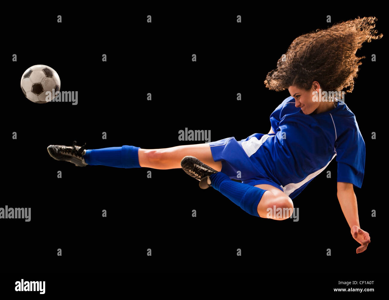 Kaukasische Fußballspieler treten Ball in der Luft Stockfoto