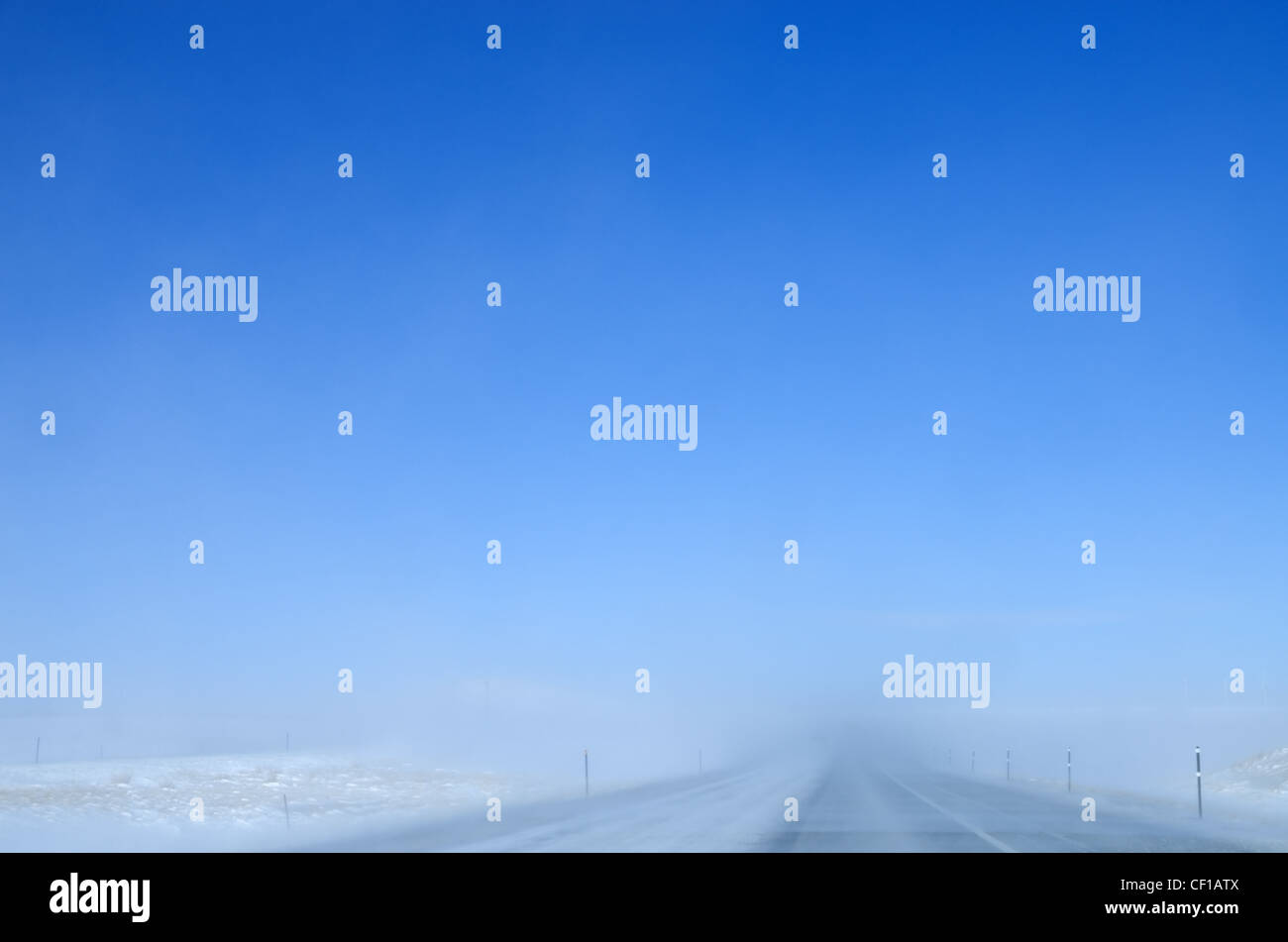 Schneetreiben auf einer Autobahn reduziert die Sichtbarkeit an einem klaren Tag Stockfoto