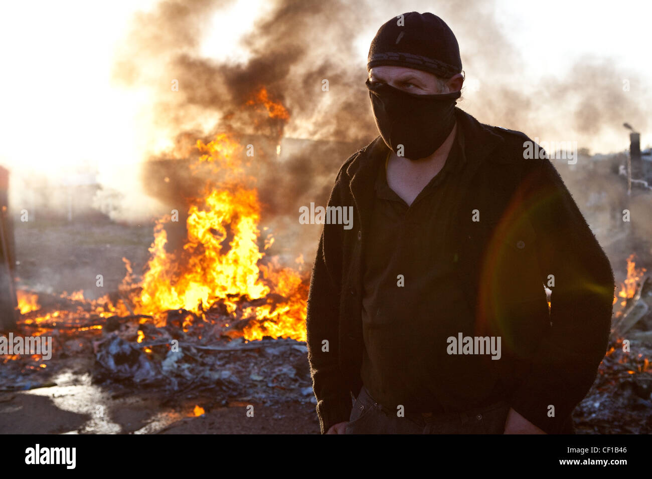 Eine einsame Aktivist Pausen zwischen den Zusammenstößen mit der Polizei neben einem brennenden Barrikade bei Dale Farm in Essex. Stockfoto