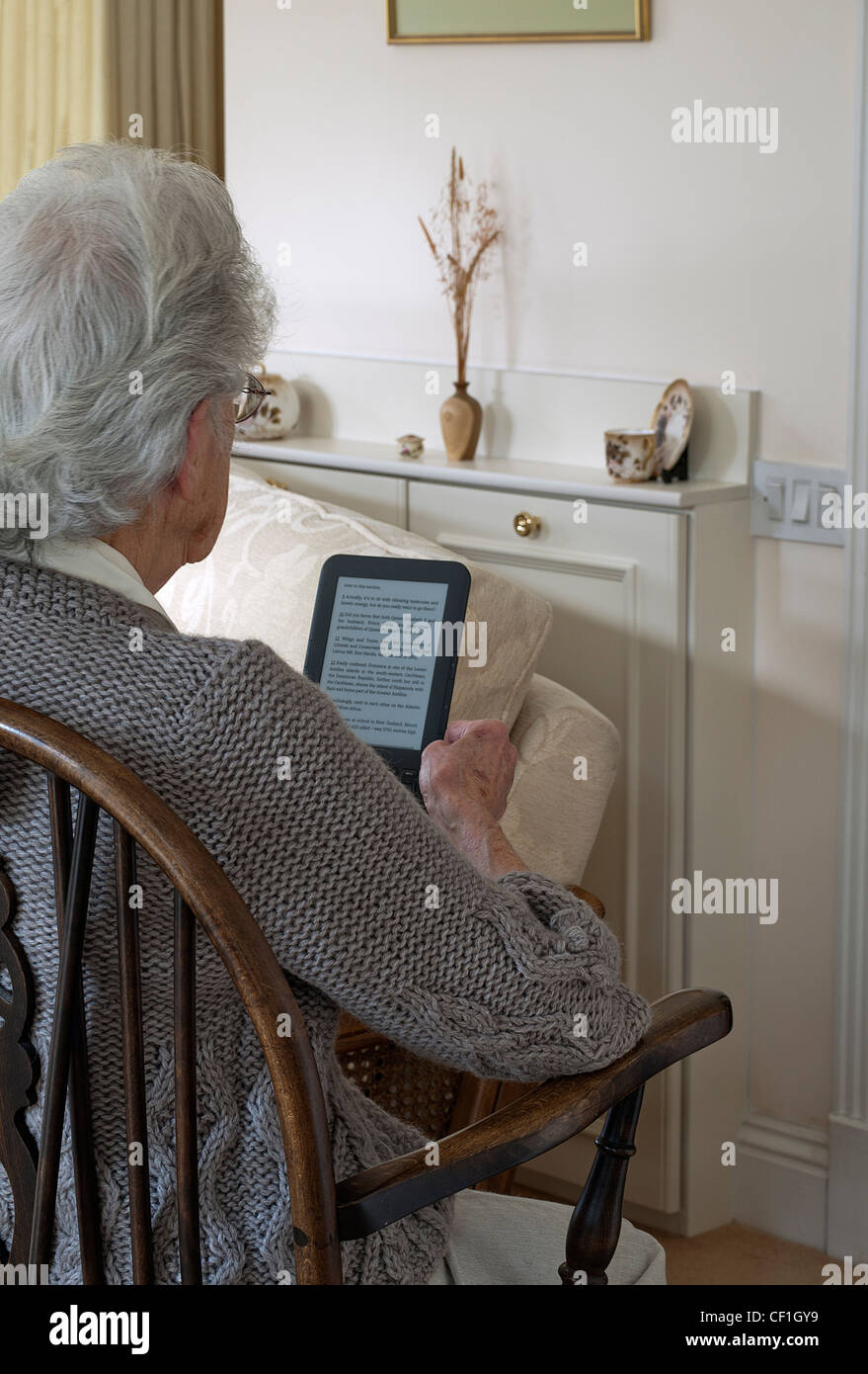 Reife Lady Lesen von einem Kindle e-Reader, Tablet, England, UK. Stockfoto