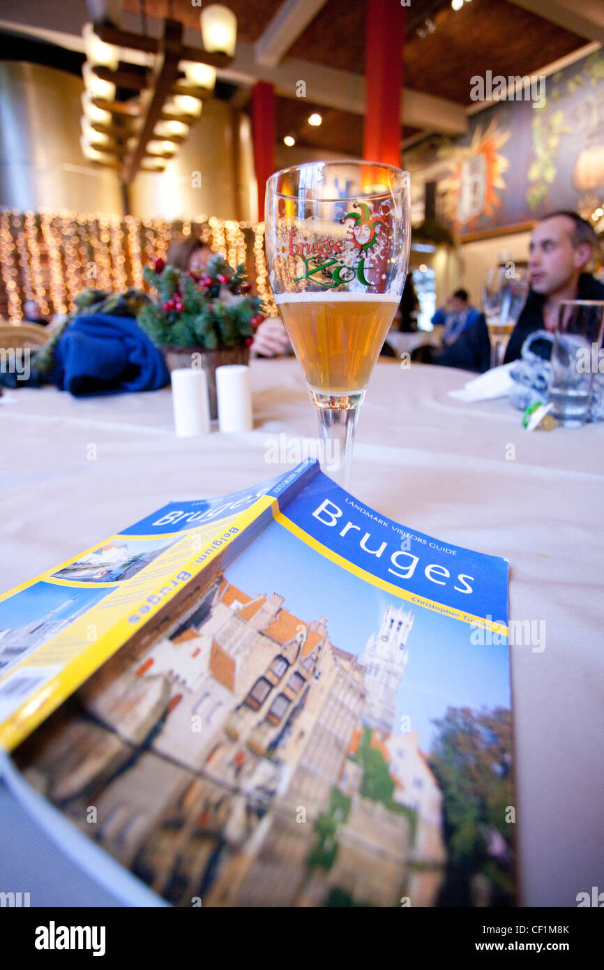 Ein Tisch in einer Bar mit einem belgischen Bier und einen Reiseführer von Brügge Stockfoto