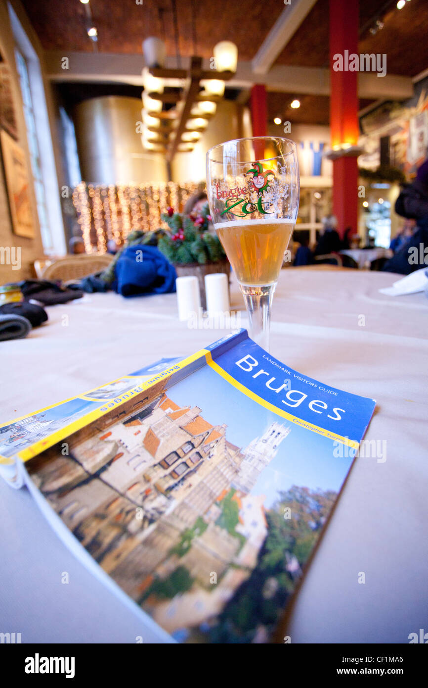 Ein Tisch in einer Bar mit einem belgischen Bier und einen Reiseführer von Brügge Stockfoto
