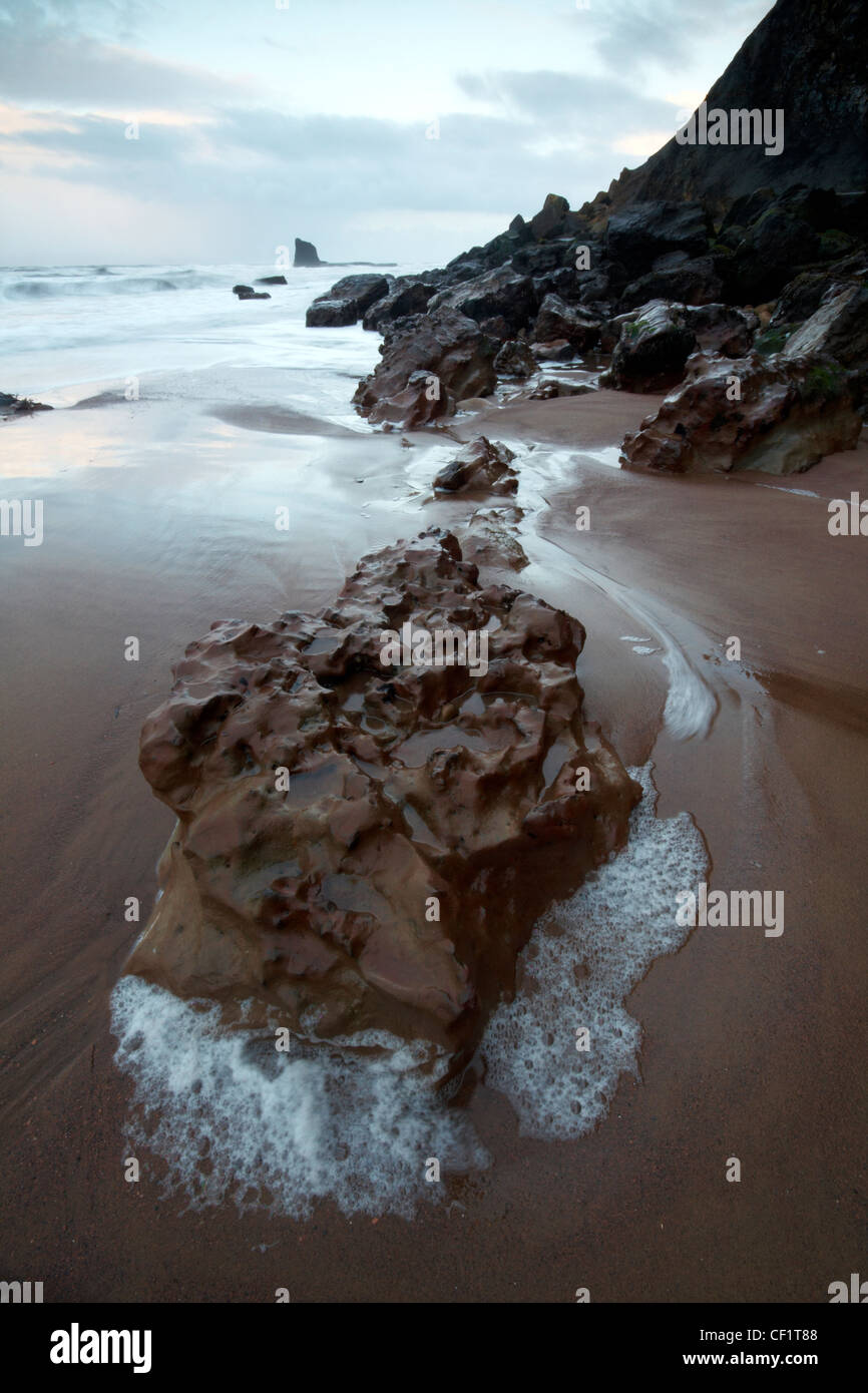 Pools von Wasser durch die Ebbtide um Felsen am Strand von gegen Bucht gebildet. Stockfoto