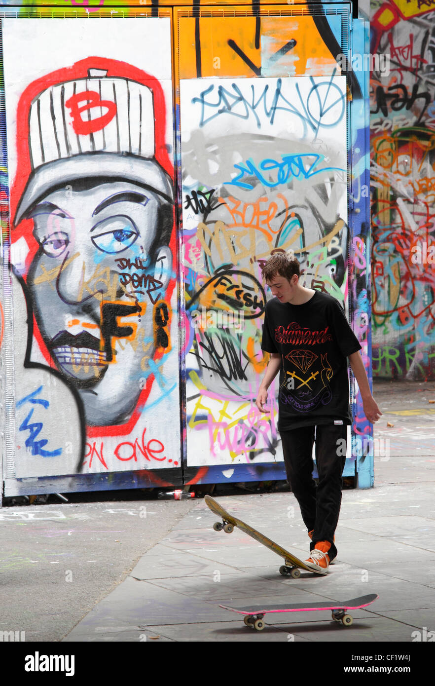 Ein Skateboarder vor dem Hintergrund der Graffiti auf der South Bank in London. Stockfoto