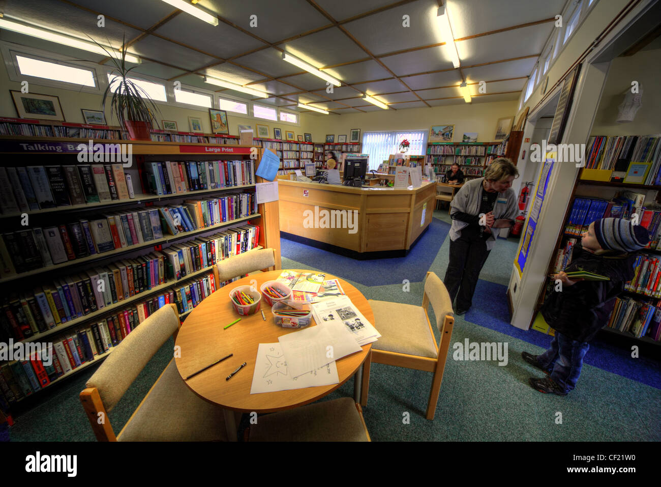 Grappenhall Bibliothek als es war im April 2010 von Warrington Borough Council geführt. Ein kleiner Junge von einem Bibliothekar geholfen Stockfoto