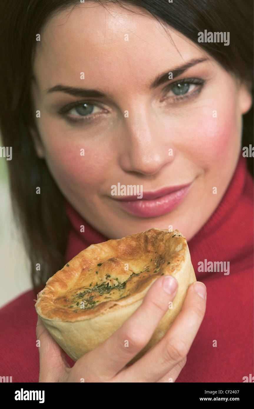 Brünette Frau mit langen Haaren, trägt ein rotes Rollkragen Springer, hält eine Torte vor Gesicht, auf der Suche, Kamera, Lächeln Stockfoto