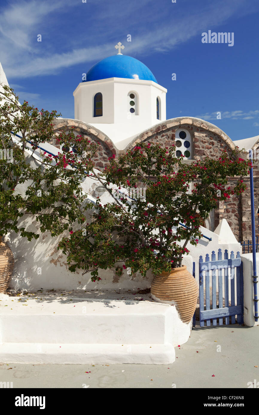 Ein Blick auf eine blaue Kuppelkirche mit traditionellen Urnen gefüllt mit Blumen und einem Zaun im Vordergrund Stockfoto
