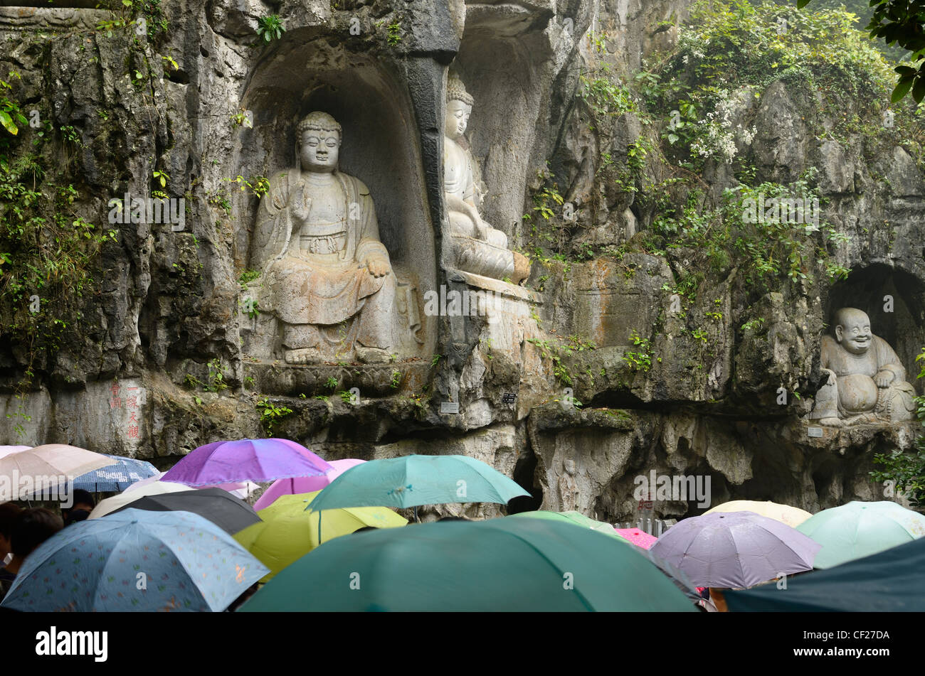 Kalkstein Buddha Skulpturen in feilai Feng im Regen mit Sonnenschirmen ling Yin Tempel Hangzhou China Stockfoto