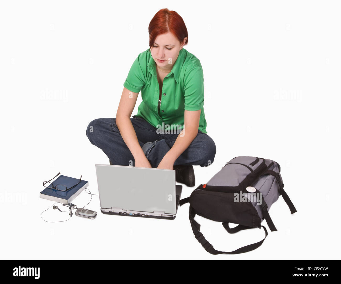 Rothaarige Teenager-Mädchen mit vielen Produkten rund um ihre Arbeit auf einem Laptop. Stockfoto