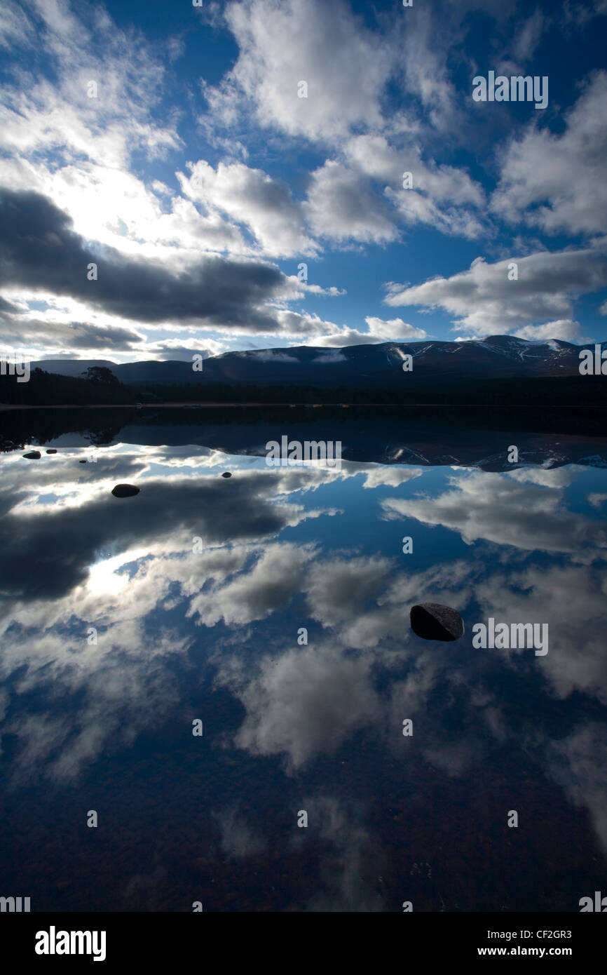 Dramatische Wolken und Cairngorm Mountains reflektiert das noch Gesicht Loch Morlich. Stockfoto
