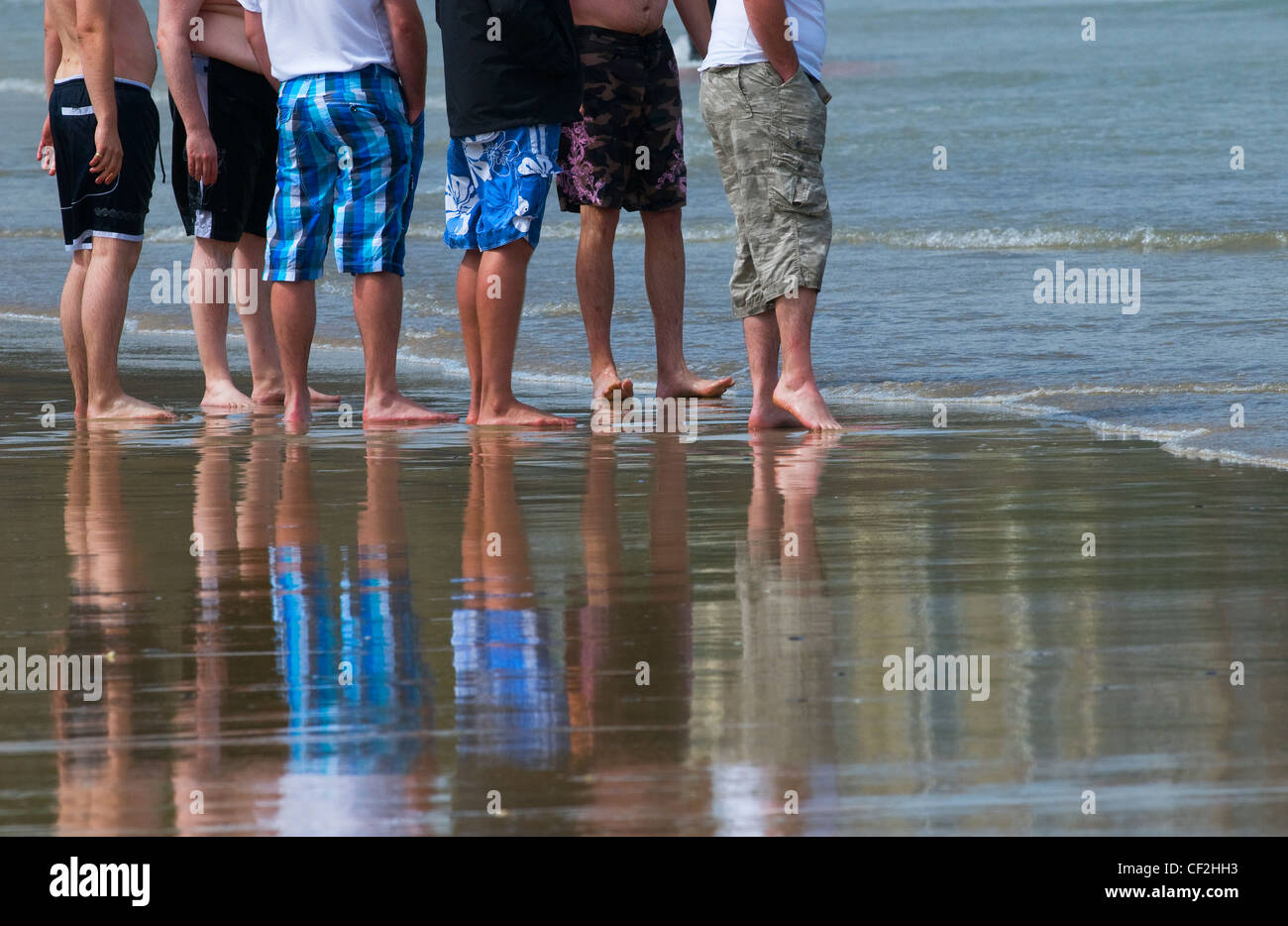 Eine Gruppe von männlichen Urlauber stehen auf dem Vorland der Strand bei Ebbe. Stockfoto
