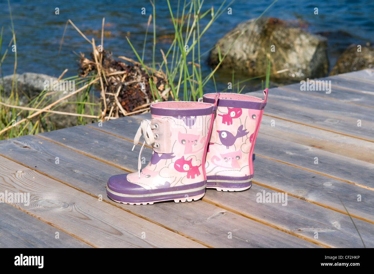 Farbenfrohe Gummistiefel des Kindes auf einem Steg Stockfoto