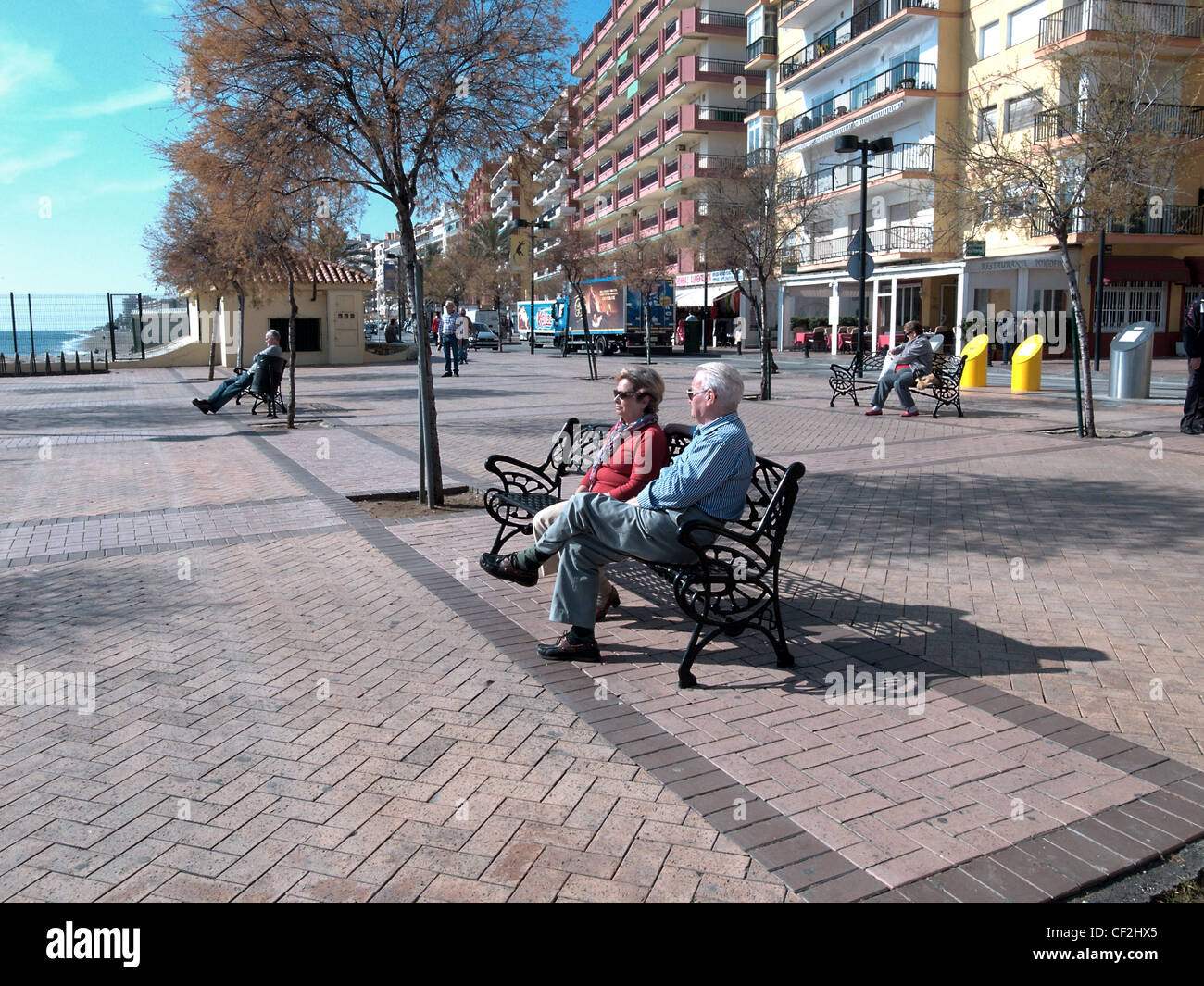 Urlauber sitzen auf schmiedeeiserne Bänke entlang der Promenade, Fuengirola, Provinz Malaga, Costa Del Sol, Andalusien, Spanien. Stockfoto