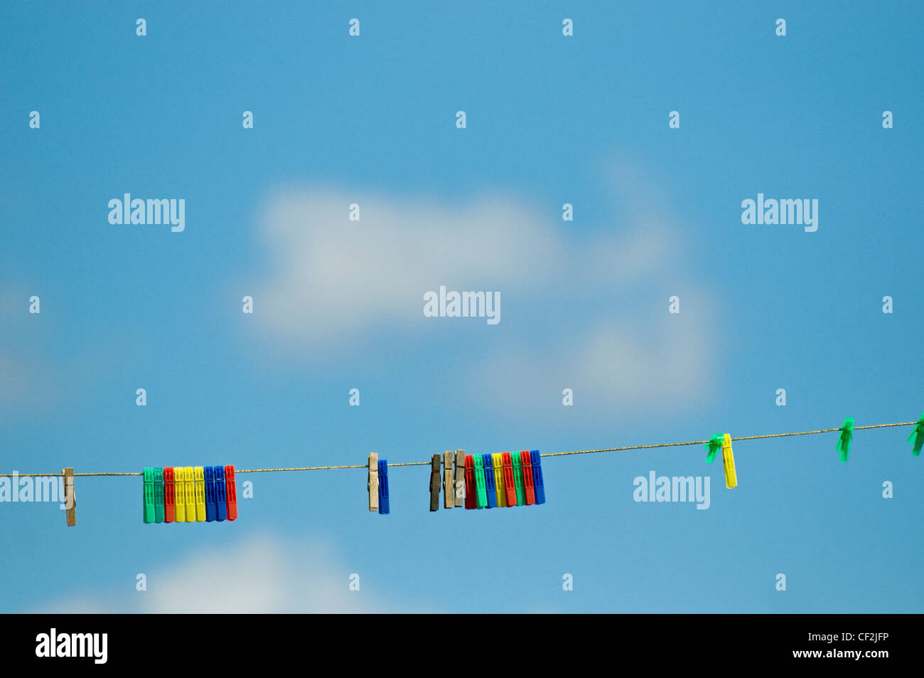 Bunte Wäscheklammern an einer Wäscheleine vor blauem Himmel. Stockfoto