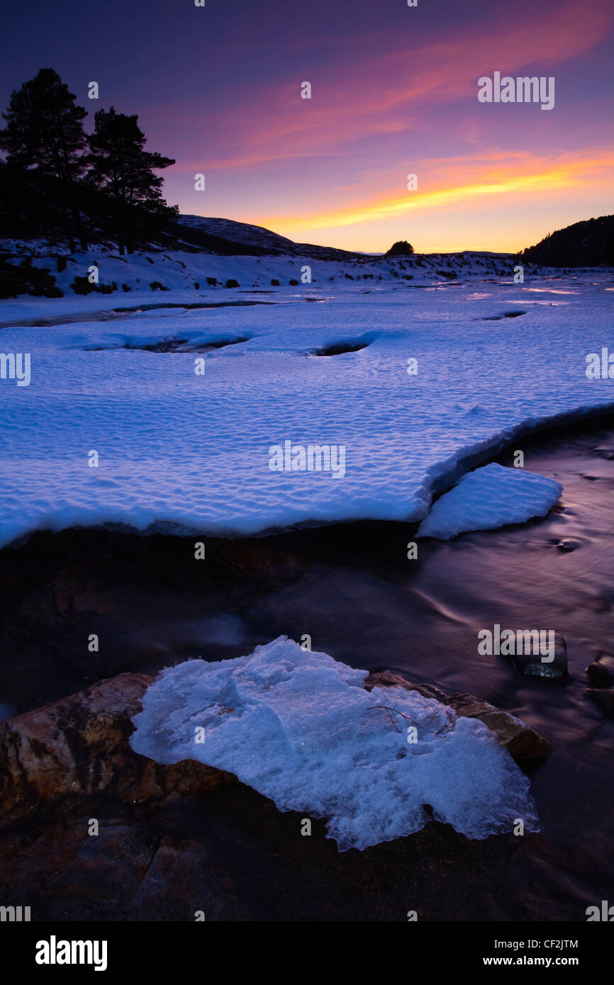 Rosa Sonnenuntergang über den zugefrorenen Fluss Dee in der Nähe der Brücke über Linn Dee abgedeckt. Stockfoto