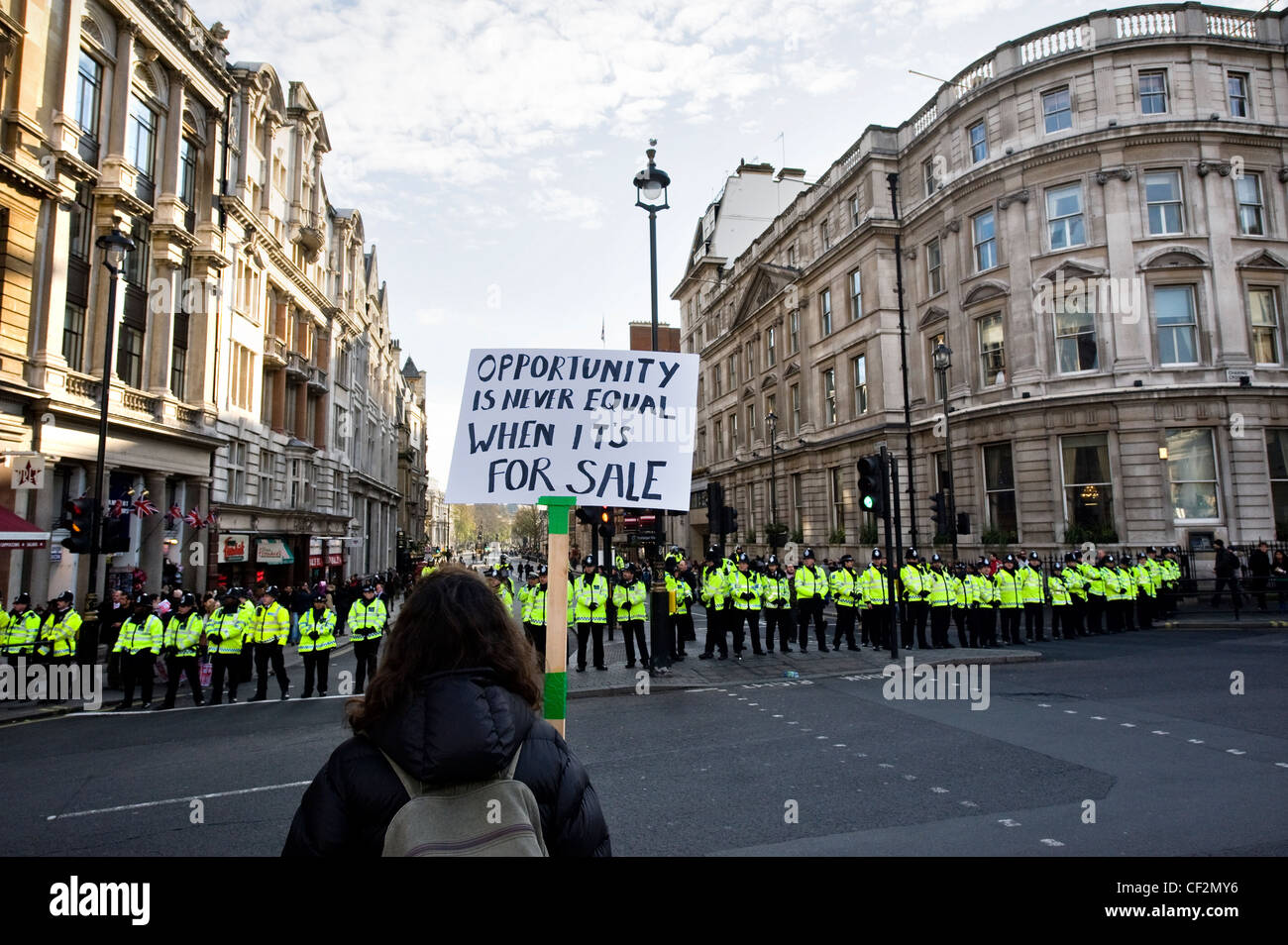Ein Demonstrant hält ein Plakat vor einer Linie der Metropolitan Police Officers bei einer Demonstration gegen die Regierung educat Stockfoto