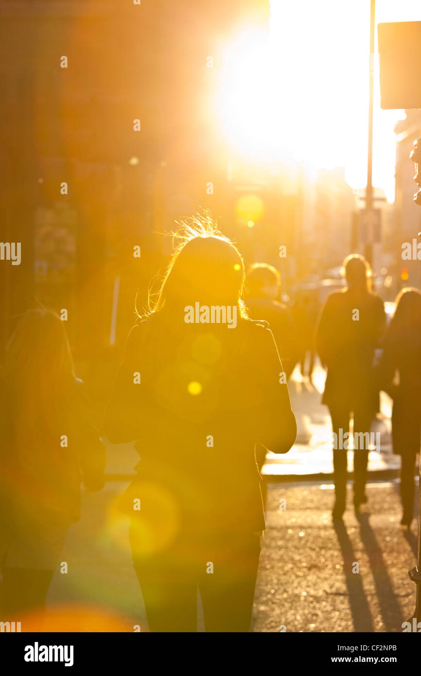Fußgänger-Silhouetten, die ins Sonnenlicht gehen, London, England, Großbritannien Stockfoto