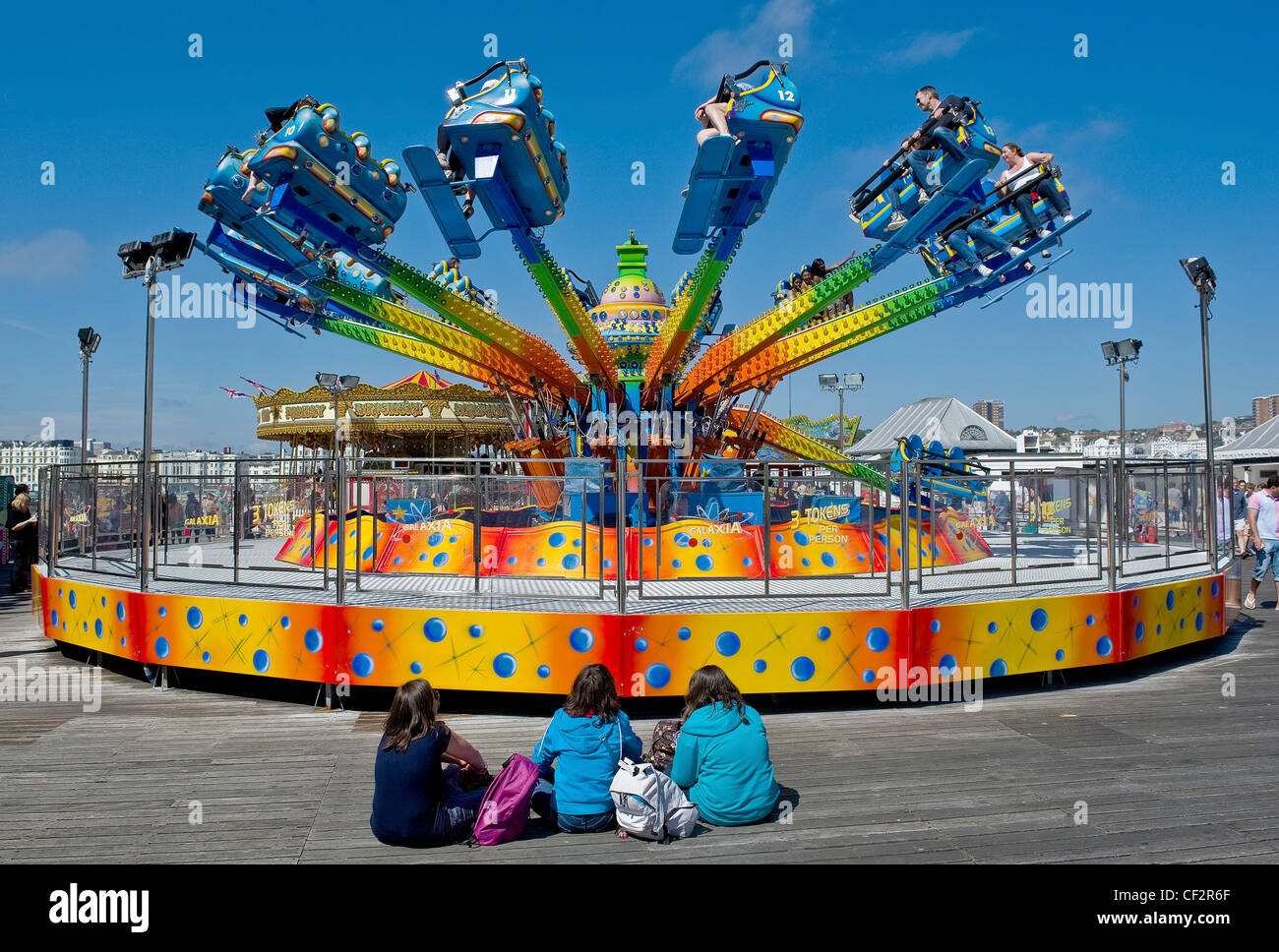 Drei junge Mädchen sitzt vor einem Messegelände fahren auf Brighton Pier. Stockfoto