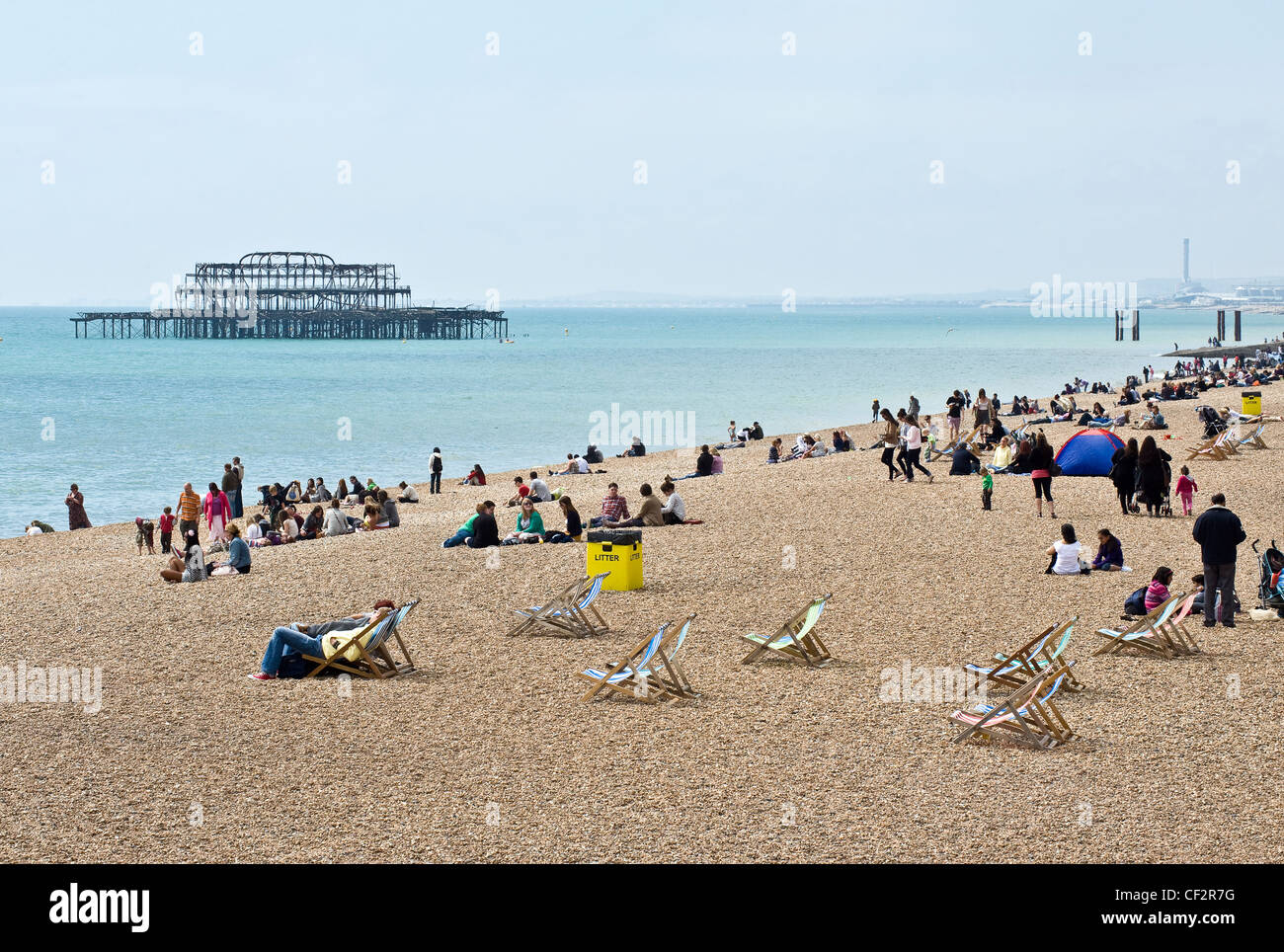 Menschen entspannen am Strand von Brighton mit den Resten der West Pier im Hintergrund. Stockfoto