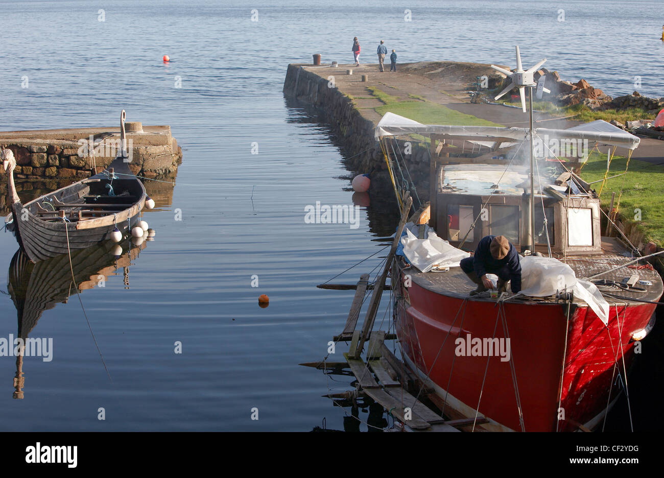 Ein Fischerboot in der Reparatur und Replik Wikingerboot im Hafen von Corrie auf der Isle of Arran. Stockfoto