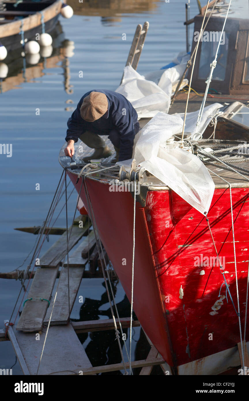 Ein Fischer Malerei sein Boot im Hafen von Corrie auf der Isle of Arran. Stockfoto