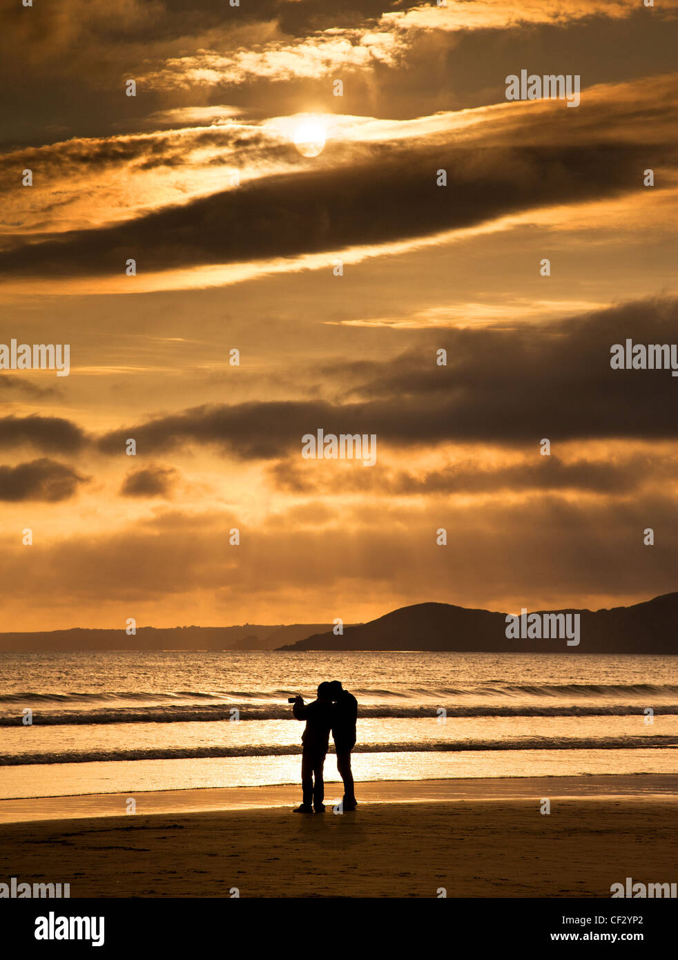 Fotograf auf Newgale Strand, Pembrokeshire, bei Sonnenuntergang. Stockfoto