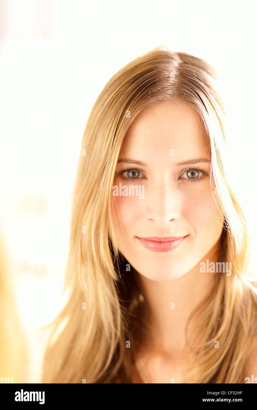 Frauen mit langen blonden Haaren getragen lose, klare faire Haut, tragen natürliche Schmink, schaut in die Kamera und lächelnd Stockfoto