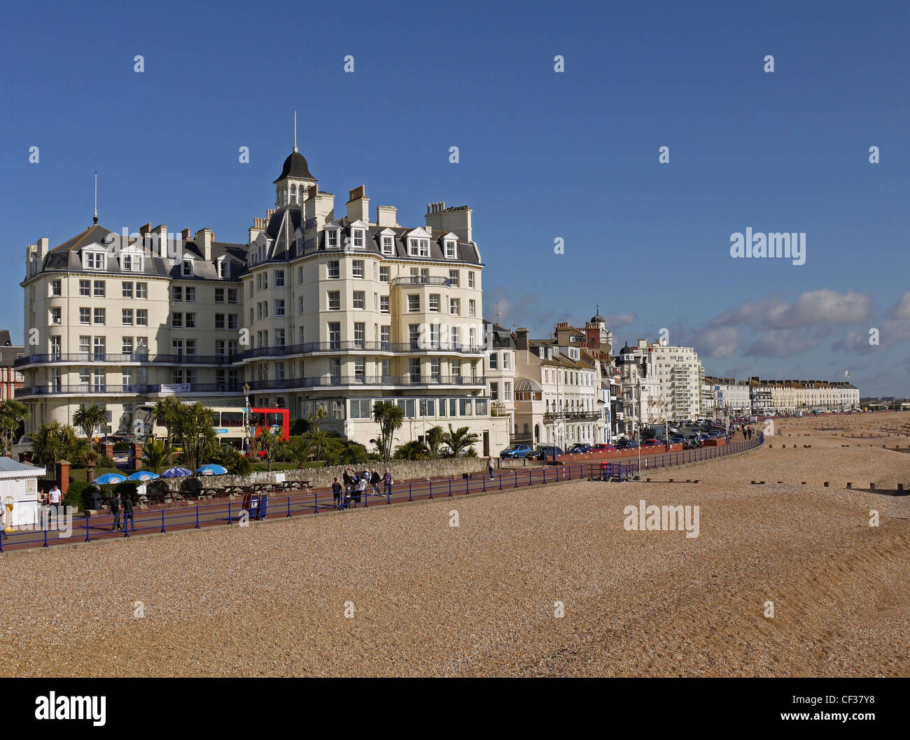 Menschen zu Fuß entlang der Promenade, vorbei an Hotels und Pensionen am Strand von Eastbourne. Stockfoto